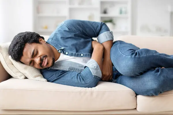 Unhealthy Young Black Man Lying Couch Home Touching His Tummy — Stock Photo, Image