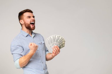Beklenmedik bir galibiyet. Genç milenyum adamı elinde dolar, panorama ve kopya uzayı ile evet işareti gösteriyor.
