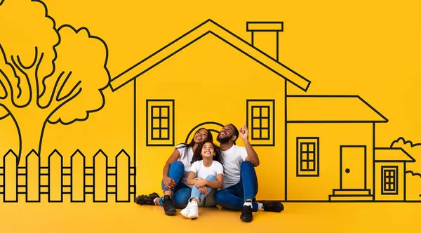 アフリカ系アメリカ人の父親と子供が黄色い壁の家に描かれた床に座っている夢を見る 不動産コンセプト ストック写真