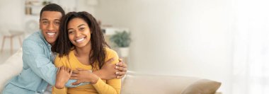 Kanepede kameraya gülümseyen Afrikalı Amerikalı çift. İnternet afişi ve fotokopi uygulamaları için ideal.