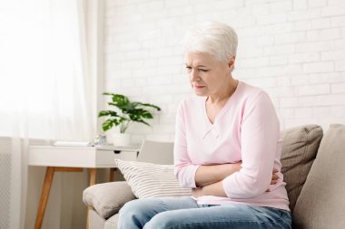 Gastrointestinal sistem çalışması yaş bozulması. Üzgün kıdemli kadın karnını tutarak, mide sorunları muzdarip, boş alan