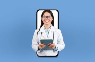 Genç bir bayan doktor, hafif ışıklandırma ve tıbbi çizelgelerle çevrili akıllı telefon ekranından görülebilen uzaktan konsültasyon sunuyor..
