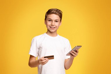 Bir elinde akıllı telefon, diğer elinde kredi kartı olan bir çocuk görülüyor..