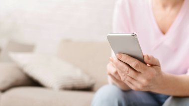 Üst düzey faaliyetleri ve emeklilik. Olgun kadın evde, modern smartphone kullanarak boş alanı