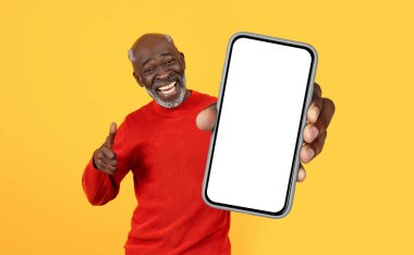 Kırmızı kazak giyen olgun siyah bir adam elinde beyaz ekranlı bir cep telefonu tutarken görülüyor.