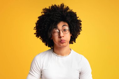 Turuncu arka planda yanakları üfleme genç siyah adam, grimacing esprili duygusal portre