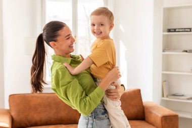 Bir kadın kucağında bir çocuğu kucaklıyor, rahatlık ve güvenlik sağlıyor. Çocuk mutlu ve güvende görünüyor. Annesinin kollarında. Onu besleyen ve koruyan bir jest yapıyor..