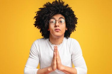 Gösterilen genç siyah adam jest, turuncu studio arka plan üzerinde oldukça Lütfen yalvaran olarak ellerini sıktı