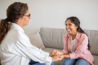Terapistinin elini tutan ve gülümseyen mutlu genç bir kadın başarılı terapi için minnettar. Ruh sağlığı konsepti