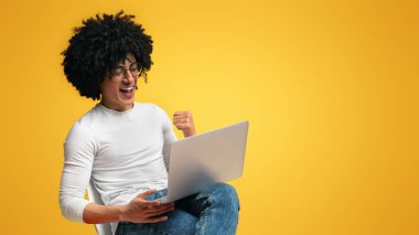 İnternetten para kazanmak. Bin yıllık adam başarı tezahürat, turuncu arka planda dizüstü bakarak