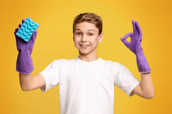 客房管理概念 可爱的男孩在清洁手套显示Ok标志和持有海绵 橙色全景背景 — 图库照片