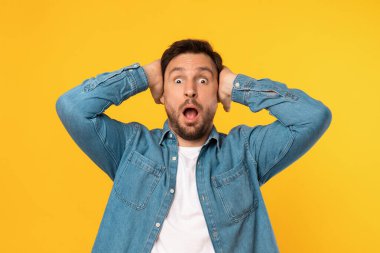 Yüzünde şaşkın bir ifade olan bir adam, gözleri sonuna kadar açık ve ağzı hafifçe sarkık. Kafasına dokunan beklenmedik bir şeyle şok olmuş ya da hazırlıksız yakalanmış gibi görünüyor.