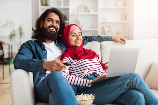 Muslimsk Par Sitter Komfortabelt Sofa Med Fokus Bærbar Plassert Foran stockbilde