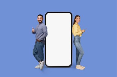 Bir erkek ve bir kadın, mobil uygulama reklamı için mavi, maket fotokopi alanında boş bir akıllı telefon görüntüsüyle ayakta duruyor