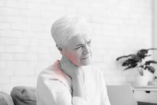 stock image Mature woman suffering from backache at home, massaging neck with hand, feeling exhausted, empty space