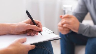 Depresif hasta ile oturum sırasında not alan psikolog, yakın çekim, panorama