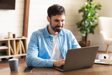 İşadamı bir masada oturuyor, dizüstü bilgisayarının ekranına odaklanıyor, çalışırken klavyeye basıyor ya da internette geziniyor. Masa basit, dikkat dağıtacak bir şey yok, ve arka plan da sade..