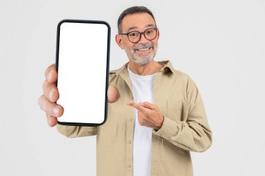 An elderly man confidently shows a blank smartphone screen, pointing to it suggesting importance or new content, isolated on a white background clipart
