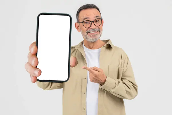 stock image An elderly man confidently shows a blank smartphone screen, pointing to it suggesting importance or new content, isolated on a white background