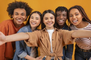 Birbirlerine sıkı sıkıya bağlı uluslararası bir arkadaş ekibi, izole edilmiş, canlı bir arka planda çoklu etnik birliği somutlaştırarak kameraya mutlu bir poz veriyor.