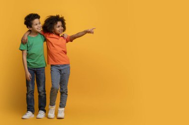 Afro-Amerikalı çocuklar canlı sarı bir arkaplanda yan yana duruyorlar. Onların mutlu ifadeleri ve dinamik pozları bir arkadaşlık ve merak duygusu iletir, kopyalama alanı
