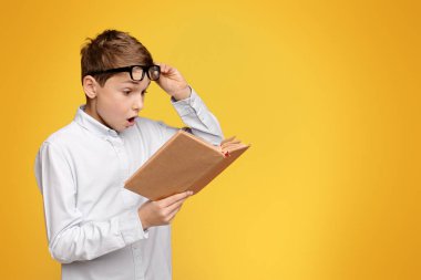 Kitap okumaya dalmış gözlüklü genç bir çocuk..