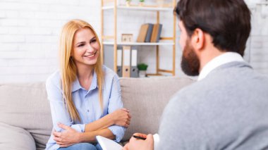 Kanepede oturan bir kadın bir erkekle konuşuyor. Her iki birey de birbirlerine bakıyor, konuşurken işaret ediyorlar. Psikologla terapi seansı