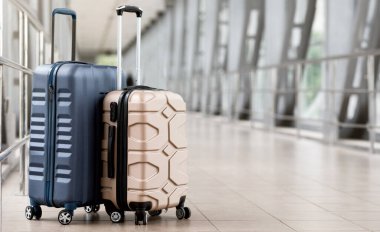 Seyahat modası. Boş havaalanı koridorunda duran iki plastik bavulun yakın çekimi, Terminal Salonunda bekleyen şık bavullar, Hava Taşıma ve Tatil Rezervasyonları