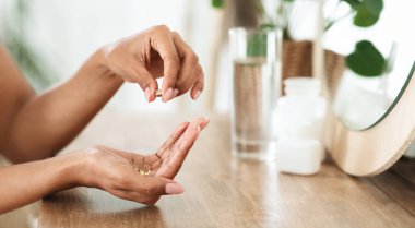 Tanınmayan Afrikalı Kadın Parlayan Cilt İçin Güzellik İlaveleri Alırken, Omega-3 Balık Yağı Kapsüllerini Ellerinde Tutarken, Yan Görünüm