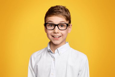 Gözlük sevimli okul çocuk portresi, boş alan ile turuncu panorama arka plan