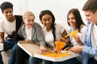 Bir grup arkadaş kanepede oturmuş, pizza dilimlerinin tadını çıkarıyorlar. Çeşitli gruplar yemeğin tadını çıkarırken gündelik sohbete dalıyorlar..
