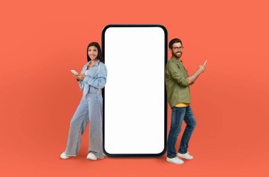 Çok ırklı aşıklar sabit bir telefonun yanında yan yana duruyorlar. İkisi de telefon ekranında bir şeye bakıyor gibi görünüyor. Konsantrasyon ve ilgi ifadeleri var..