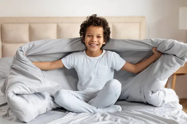 Cheerful Young African American Boy Sits Cross Legged Bed Spreading — Stock Photo, Image
