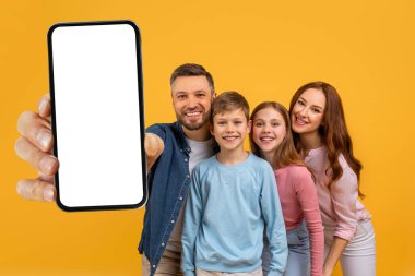 Dört kişilik neşeli bir aile, babasının kollarını uzatarak beyaz ekranlı akıllı telefonu göstererek etkileşimli bir sunum ya da bir maket sunumu öneriyor..