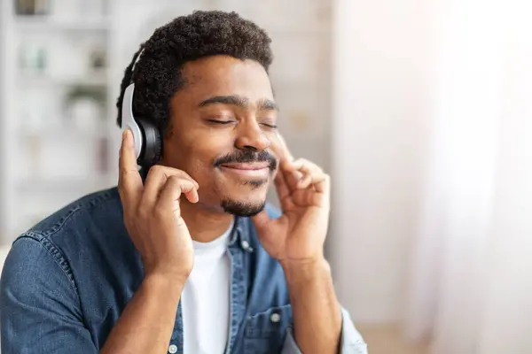 African American Man Seated Couch Engrossed Listening Music Appears Relaxed Stock Image