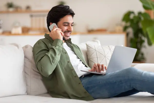 Arab Man Seated Couch Engrossed His Laptop Phone Appears Focused Royalty Free Stock Images