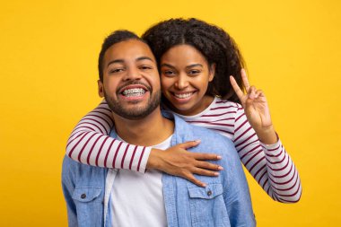 Afro-Amerikalı kadın ve erkek birbirlerine sıkıca sarılıyorlar, yüzlerinde kocaman bir gülümsemeyle. İkisi de birbirlerinin kollarında gerçekten mutlu ve mutlu görünüyorlar..