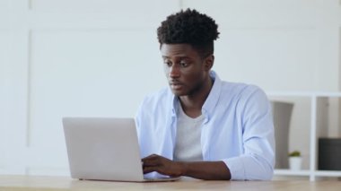 İlginç bir içerik. Genç Afro-Amerikan bir adam bilgisayarla merkez büroda çalışıyor.