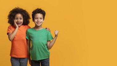 Canlı gömlekler giyen iki Afro-Amerikalı genç, parlak turuncu bir arka fonun önünde poz veriyorlar, fotokopi alanını gösteriyorlar ve suratlarını buruşturuyorlar.