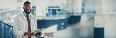İş kıyafetleri içindeki mutlu siyah adam ve koruyucu gözlükler takan tıbbi bilimci dijital tablet kullanan, verileri analiz eden, iş yerinde poz veren, kopya alanı olan bir panorama. İş ve Meslek kavramı