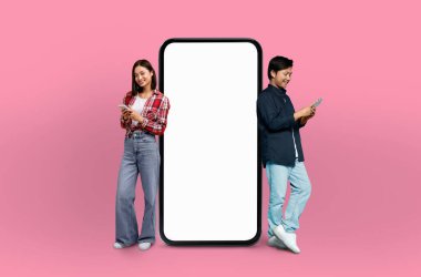 Sahnede, her ikisi de sırıtan genç bir Çinli çift, kusursuz pembe bir arka planda, gerçek boyutta bir akıllı telefon modelinin yanında yer alıyor..