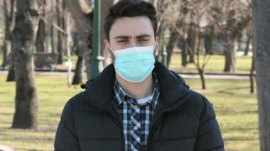 Coronavirus önleme. Şehir parkında koruyucu sağlık maskesi takmış genç bir adam