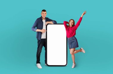 Duygusal bir erkek ve bir kadın ellerinde boş beyaz bir telefonla birlikte duruyorlar. Arkaplan, denekler için basit bir zemin sağlayan sade mavi bir renktir..