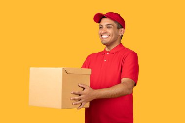 Kırmızı üniformalı ve şapkalı neşeli bir teslimatçı gülümserken elinde bir karton paket tutuyor..