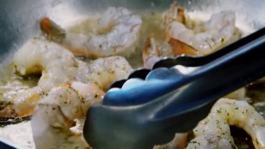 Şefin yemek maşasıyla karides çevirmesine, tavada deniz ürünleri kızartmasına yakın durun.
