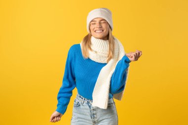 Mavi bir kazak ve beyaz bir eşarp giyen bir kadın tasvir ediliyor. Yüzünde tarafsız bir ifadeyle ayakta duruyor ya da oturuyor..