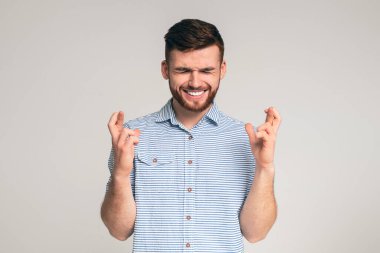 Gözleri kapalı genç adam, şans diliyor. Gri stüdyo geçmişinde şans diliyor.