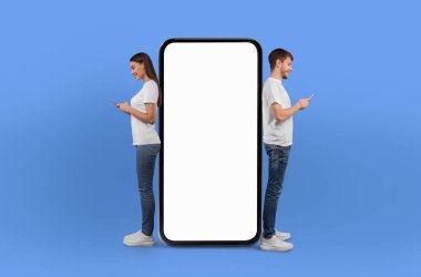 Bir erkek ve bir kadın büyük ekranlı bir telefonun yanında duruyorlar, bir konuşmayla meşgul gibi görünüyorlar ya da cihazın içeriğini görüyorlar. Her iki şahıs da önlerindeki ekrana odaklanmış görünüyor..