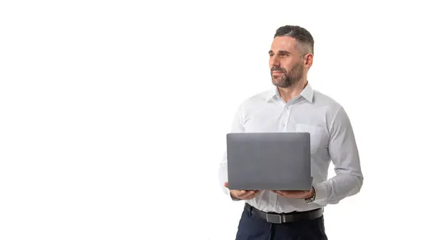 stock image A professional businessman, dressed in a white shirt and dark pants, stands confidently holding a laptop in a bright office environment with a clean, white background, copy space