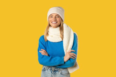 Bu sahnede mavi bir kazak ve beyaz bir şapka giyen bir kadın tasvir ediliyor. Yüzünde tarafsız bir ifadeyle dikilip doğrudan kameraya bakıyor.